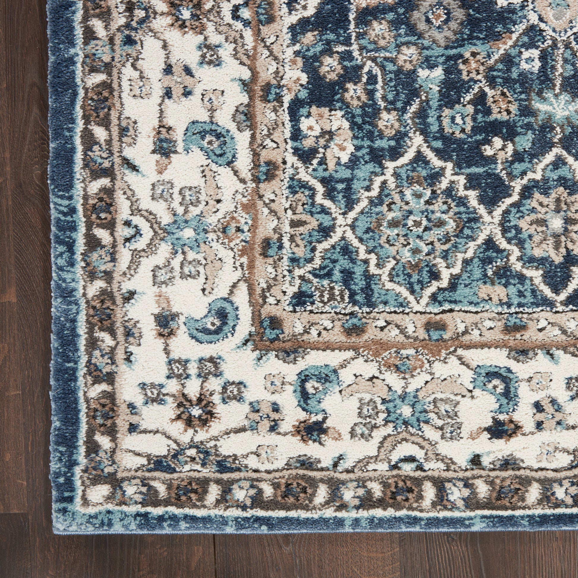 Turquoise, cream, and brown oriental-style area rug corner on dark wood floor with intricate floral medallion border.