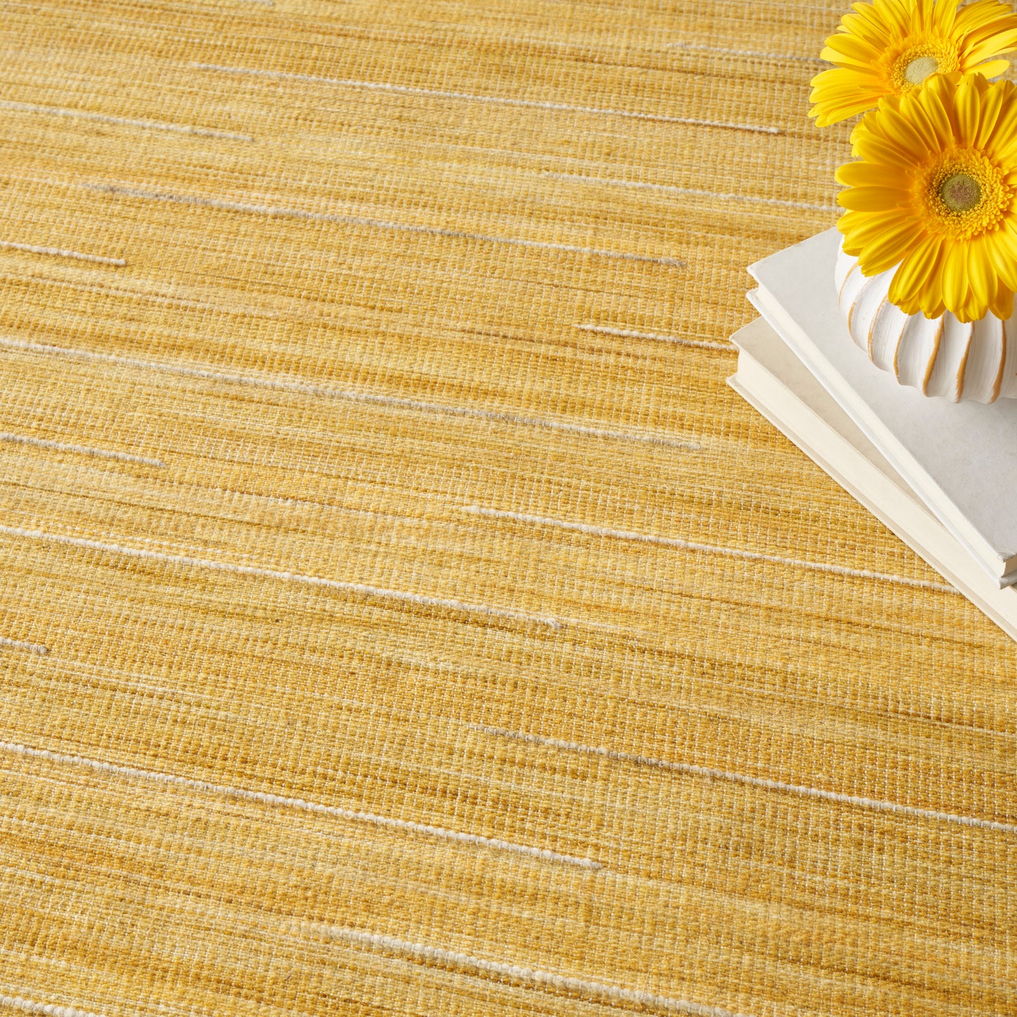 Golden yellow woven straw placemat with a stack of white books and a bright sunflower in the corner.