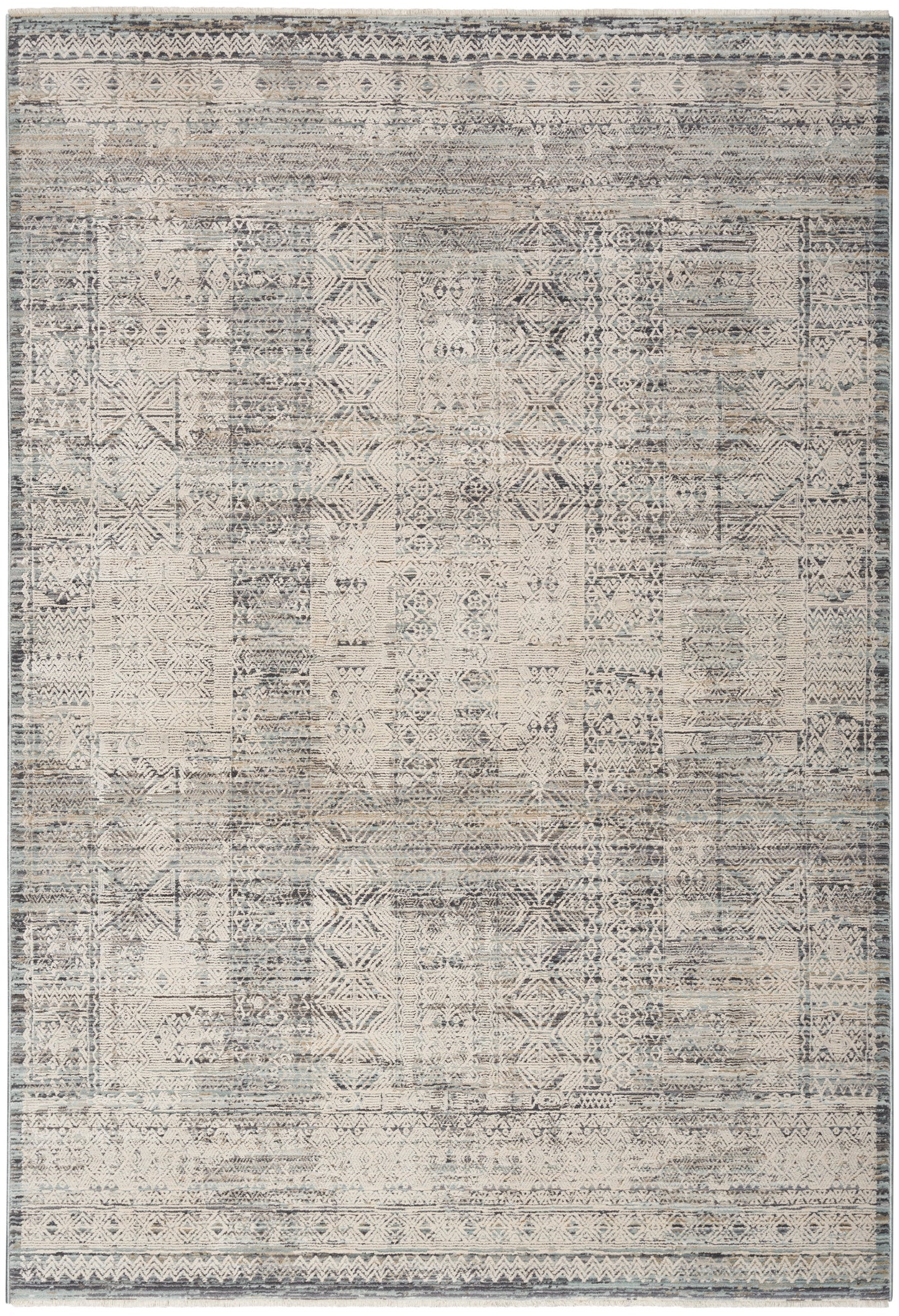 Distressed vintage patchwork rug with geometric motifs in muted beige, gray & blue, framed by subtle borders.