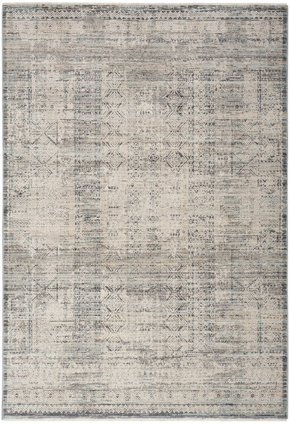 Distressed vintage patchwork rug with geometric motifs in muted beige, gray & blue, framed by subtle borders.