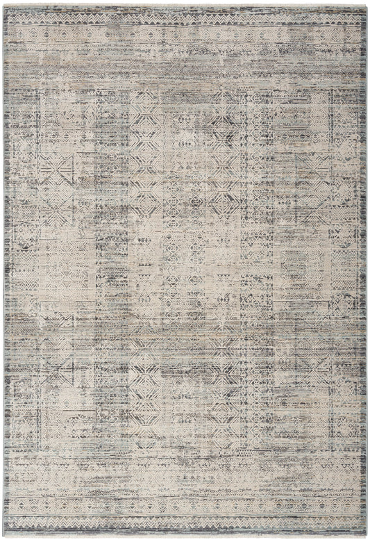 Distressed vintage patchwork rug with geometric motifs in muted beige, gray & blue, framed by subtle borders.