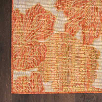 Orange floral tapestry rug with large blossoms on beige background, bordered in orange and placed on dark wood floor.