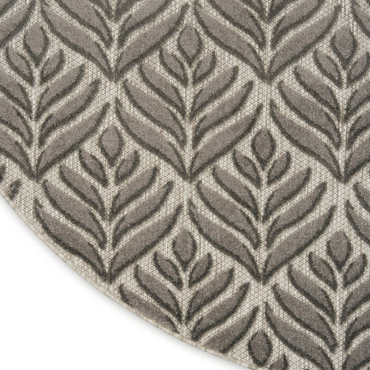 Textured woven rug with raised taupe leaf motif on beige background; round rug.