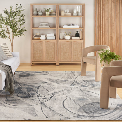 Bright Scandinavian living room with light wood shelving, woven cabinet doors, beige sofa, gray abstract rug, and plants.