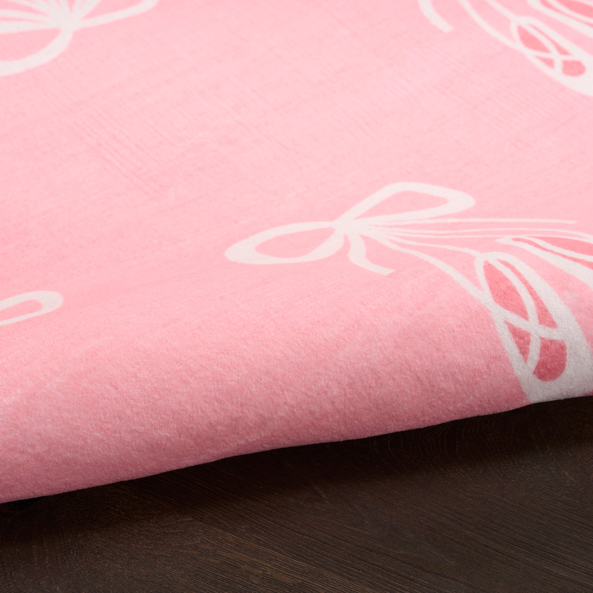 Soft pink rug with white bow prints; smooth cotton-like material, kid-friendly floor rug, size 5' x 7'.