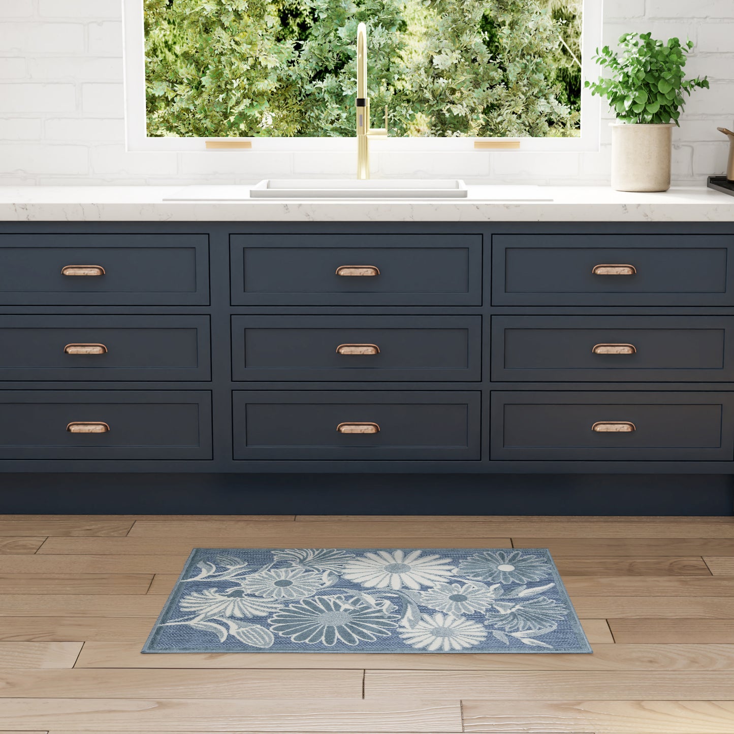 Blue floral outdoor rug on wood floor with greenery in view.