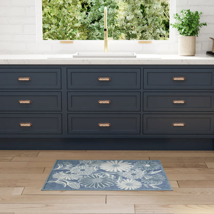 Blue floral outdoor rug on wood floor with greenery in view.