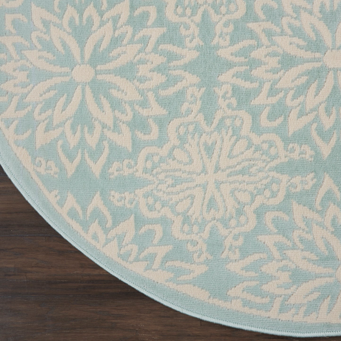 Round light-blue rug with white snowflake motifs on a dark-wood floor.