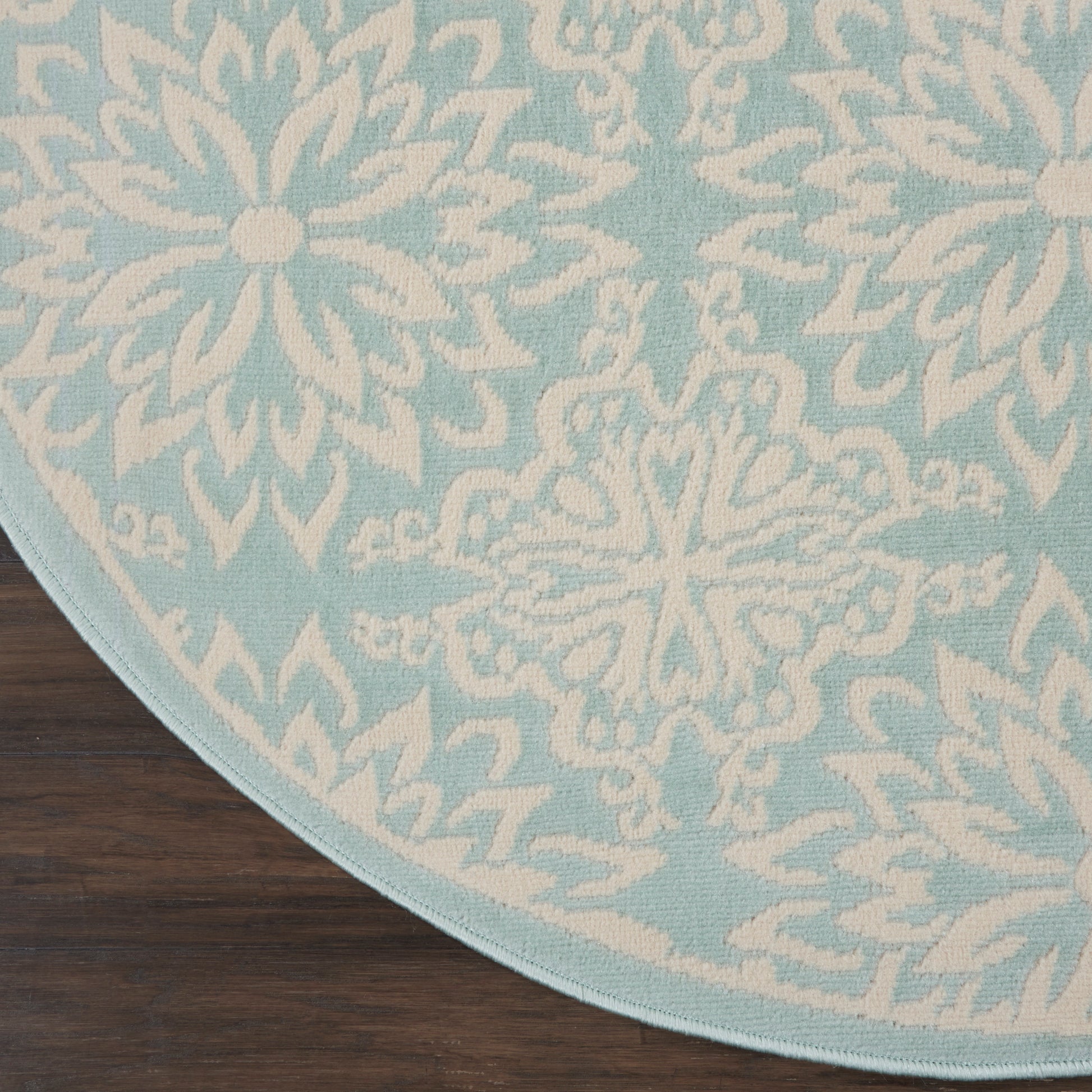 Round light-blue rug with white snowflake motifs on a dark-wood floor.