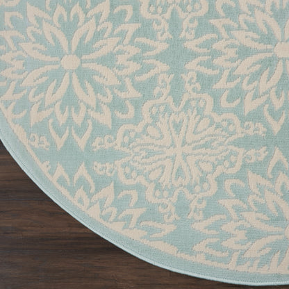Round light-blue rug with white snowflake motifs on a dark-wood floor.
