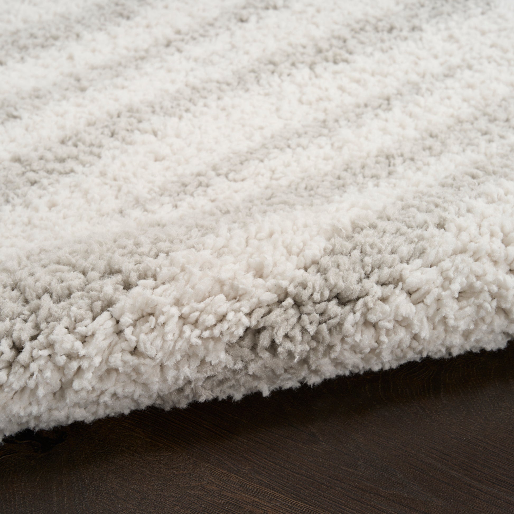 Cream beige shag rug with dense fluffy pile on dark wood floor.