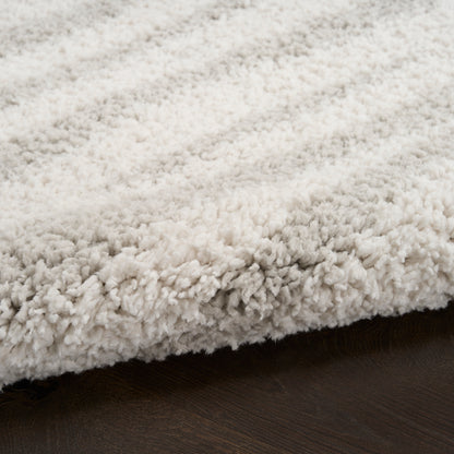 Cream beige shag rug with dense fluffy pile on dark wood floor.