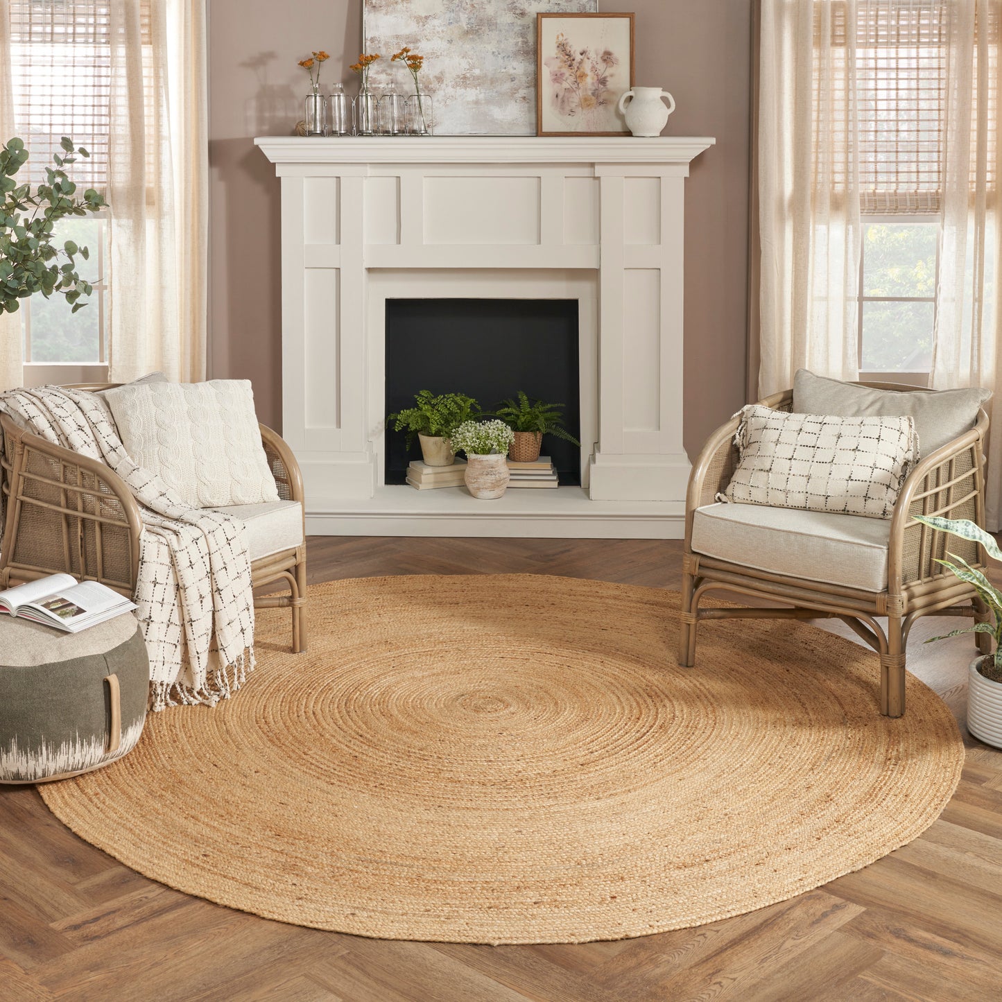 Cozy living room featuring a white fireplace mantle, two rattan chairs, and a large circular jute rug in warm neutrals.