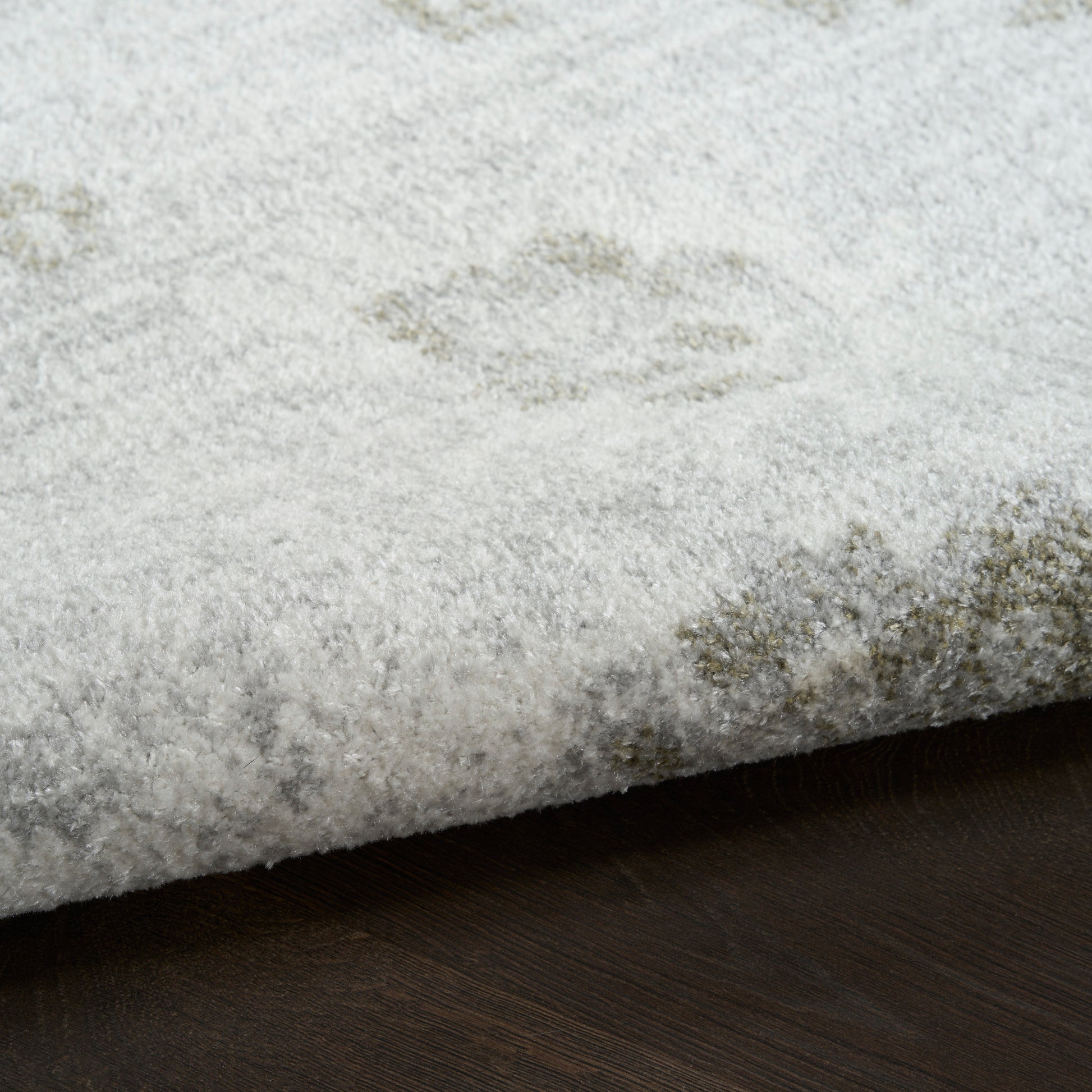 Soft light-gray rug with plush pile and subtle abstract pattern on dark wood floor.