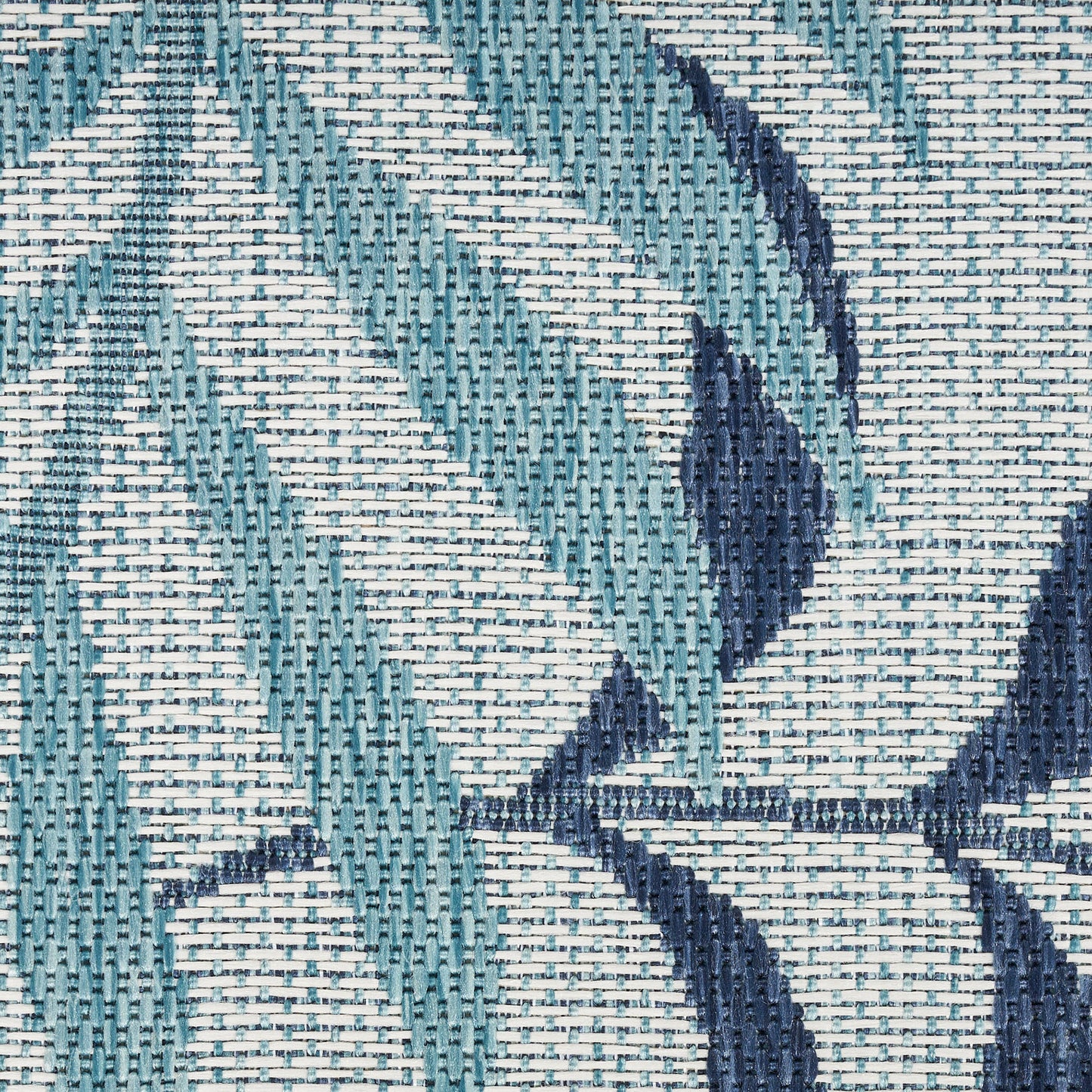 Close-up of teal and navy woven fabric with geometric leaf pattern and textured weave.