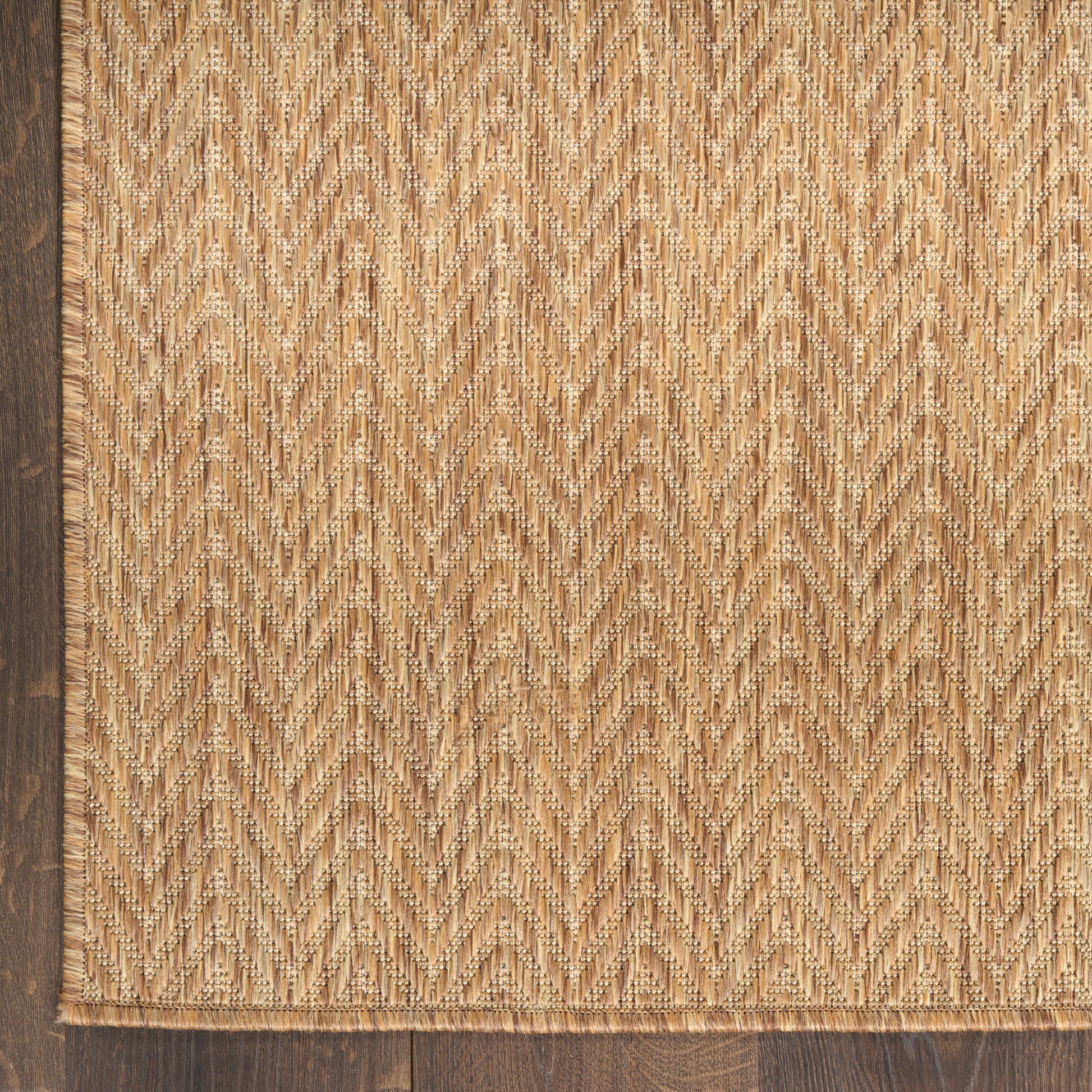 Natural beige jute rug with chevron/herringbone weave and dark brown border.