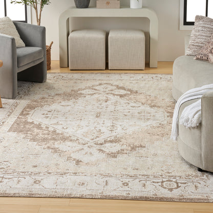 Beige vintage-style area rug with faded oriental motif, plush texture, in a modern gray living room with sofa and ottomans.