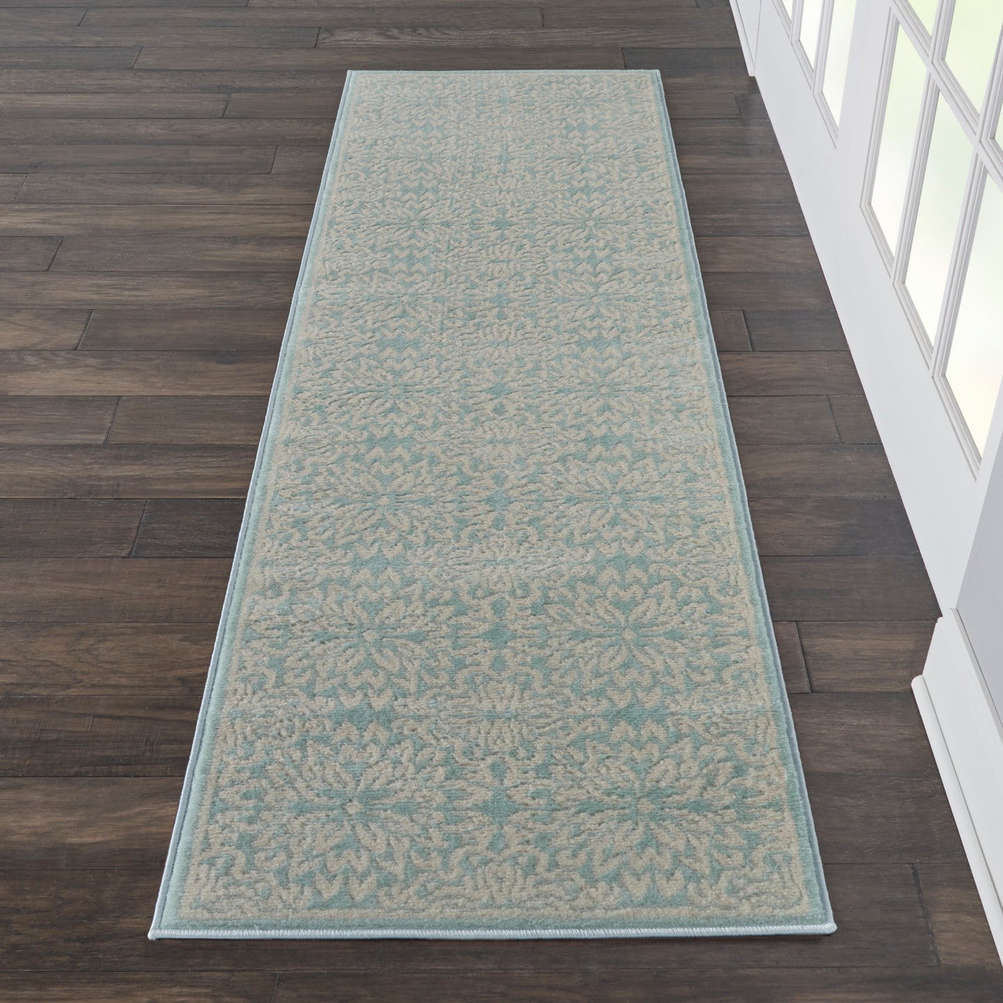 Teal runner rug with beige damask pattern & pale blue border on dark hardwood floor