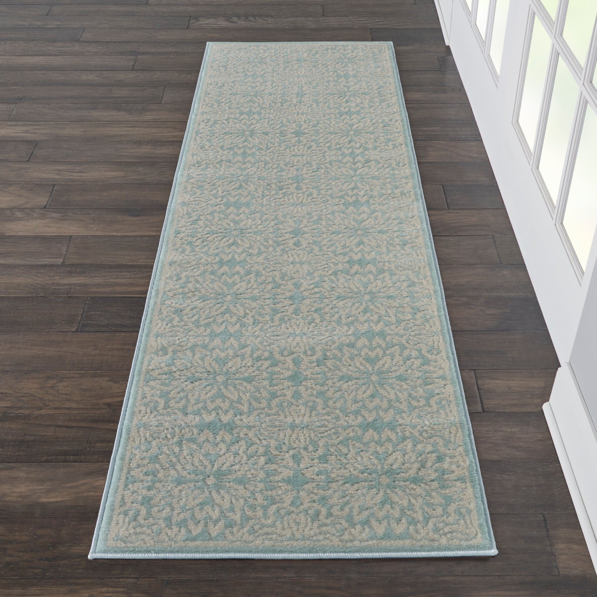 Teal runner rug with beige damask pattern & pale blue border on dark hardwood floor