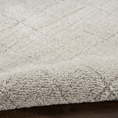Beige plush high-pile shag rug with a subtle geometric pattern, edge on dark wood floor.