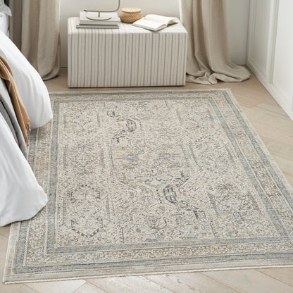 Beige-gray distressed Persian-style area rug on light wood floor in a bedroom with a striped ottoman.