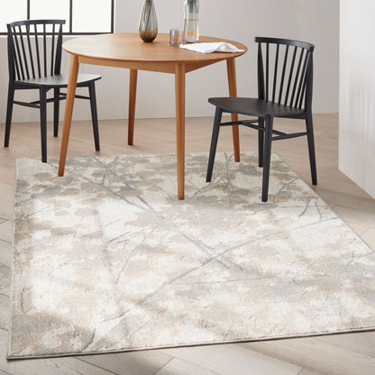 Beige abstract-pattern area rug under a round light-wood dining table with black spindle chairs; modern dining room scene.