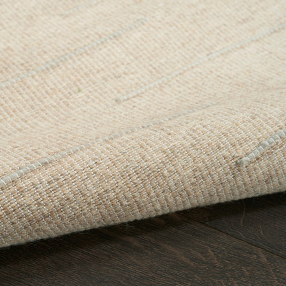 Beige woven rug with subtle gray stripes, folded edge resting on dark wooden floor.