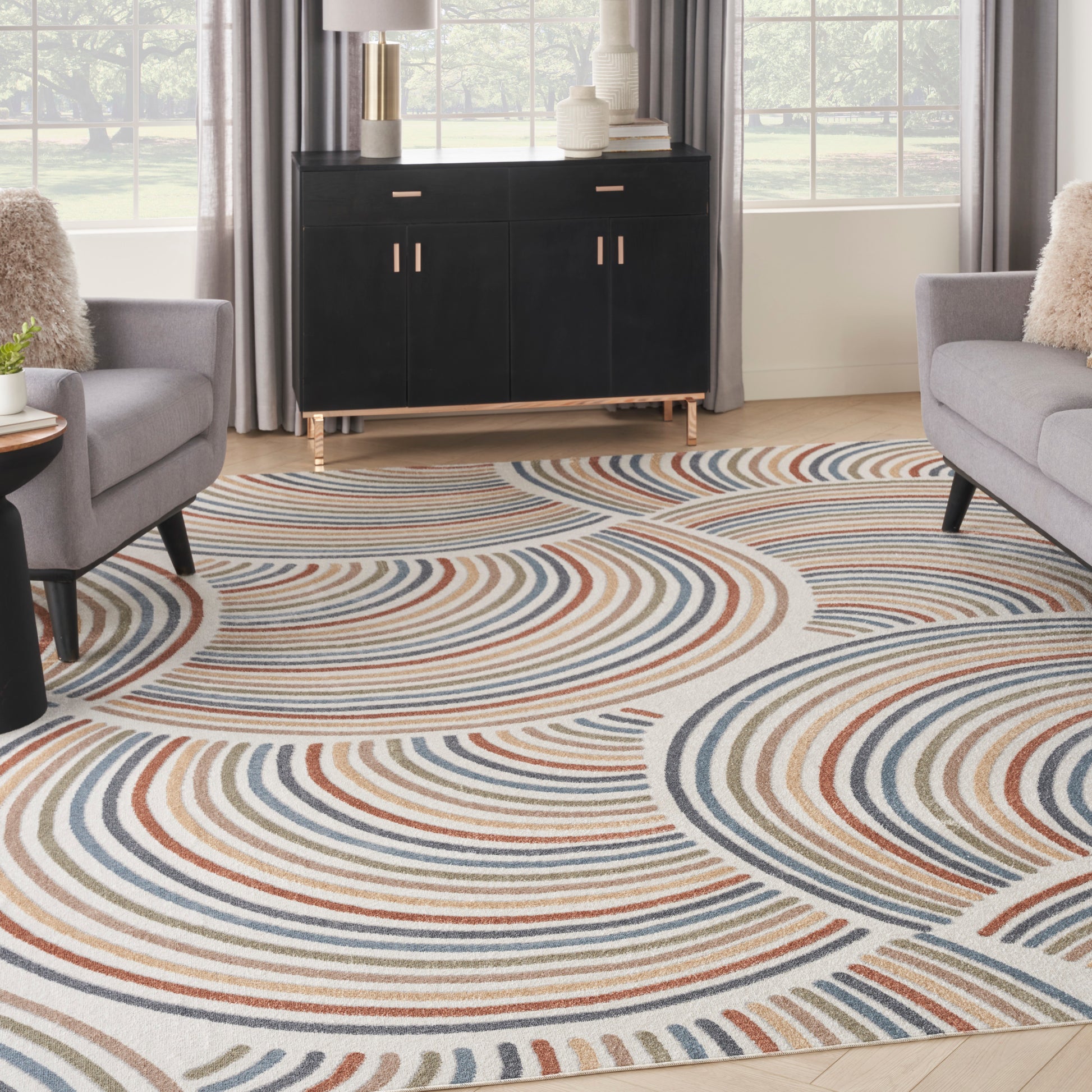 Living room with a concentric arc-pattern area rug in beige, blue, and rust; black mid-century cabinet, gray lounge chairs.