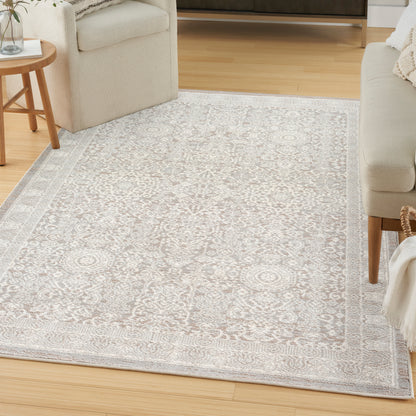 Beige-gray oriental patterned area rug with a light border in a cozy living room beside cream sofa and wood furniture.