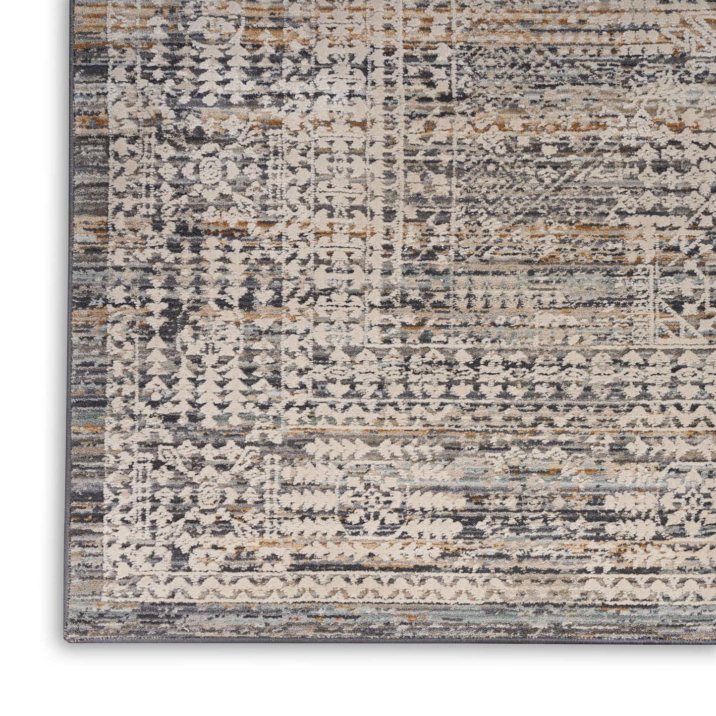 Close-up of a distressed patterned rug in muted blue, beige, gray, and tan with geometric motifs and a dark border.