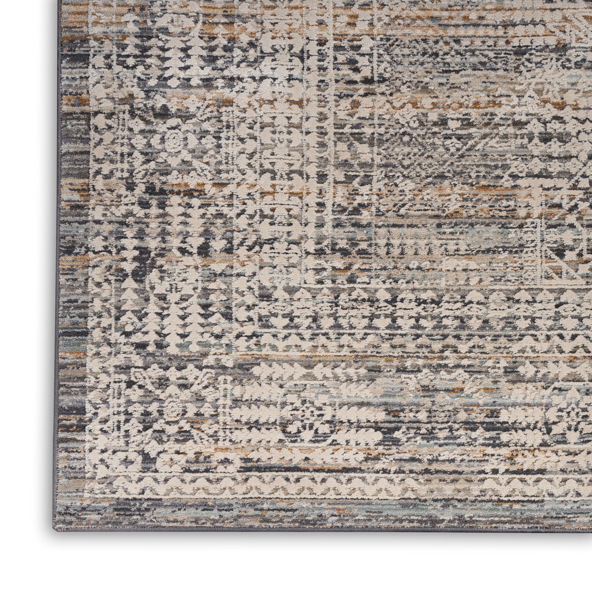 Close-up of a distressed patterned rug in muted blue, beige, gray, and tan with geometric motifs and a dark border.