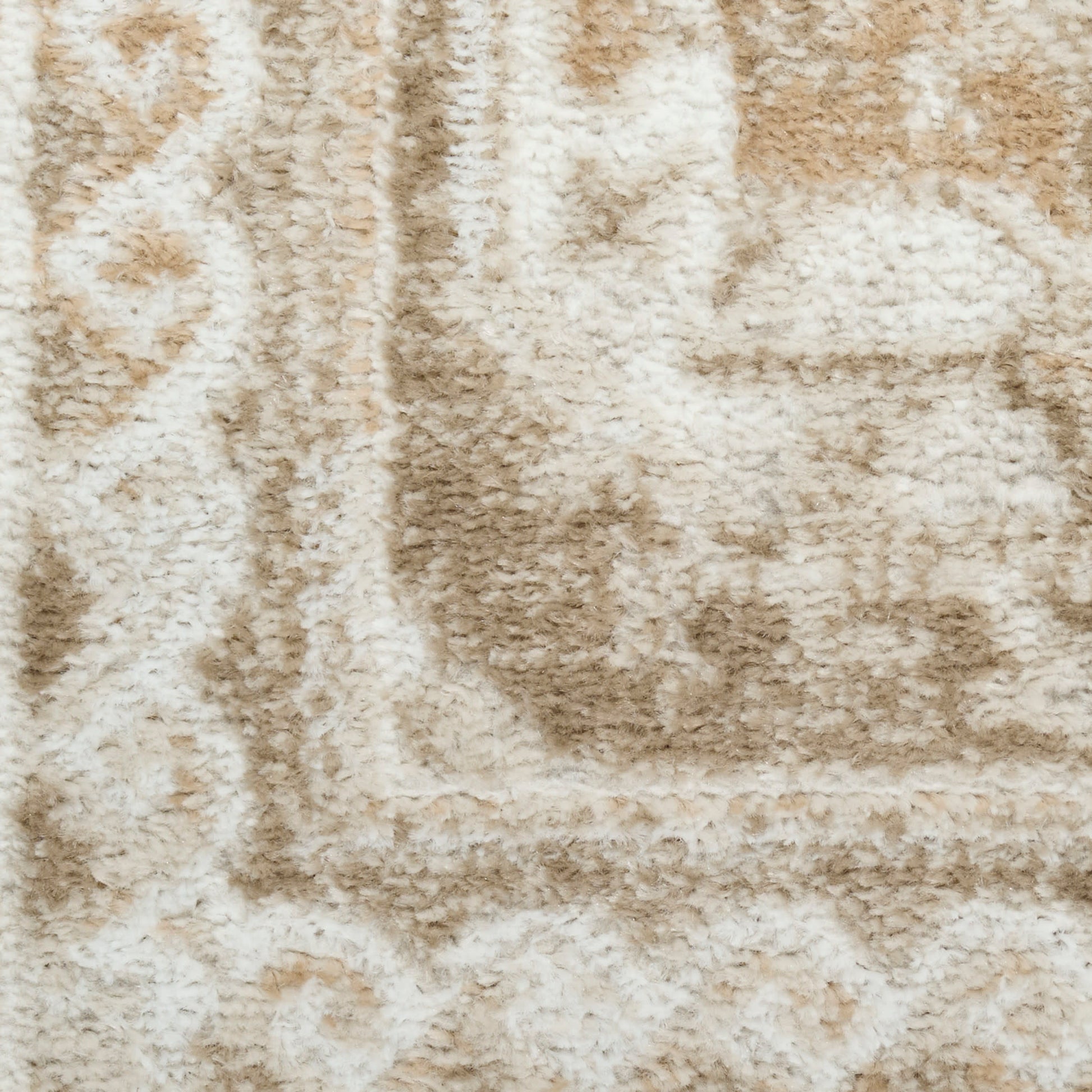 Close-up of beige and cream shag rug with plush pile and subtle geometric border.