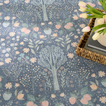 Blue botanical textile with pastel tree and floral pattern; woven basket and pink tulips in corner.