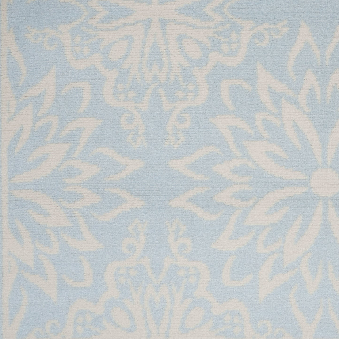 Light blue rug with a white damask floral pattern and woven texture, 5' x 7'.