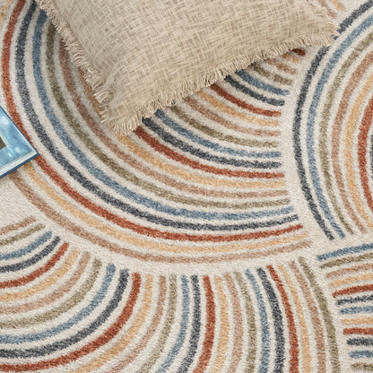 Beige woven rug with multicolor curved arc stripes in blue, tan, brown and orange; beige textured pillow resting on it.