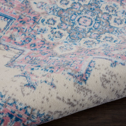 Close-up of pastel blue and pink patterned rug with cream background, showing floral motifs and a folded corner on a wooden floor.