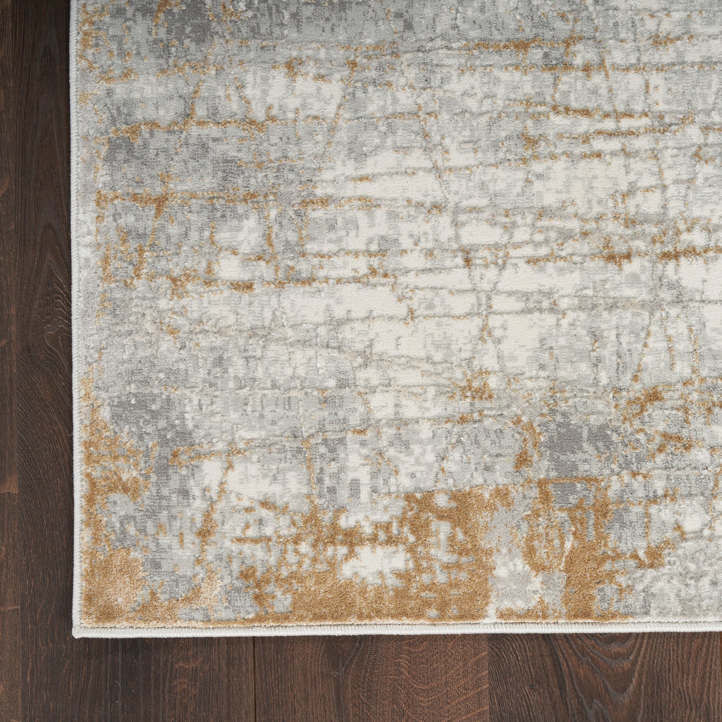Abstract distressed area rug in gray, ivory, beige and rust tones on dark wood floor; modern woven design.