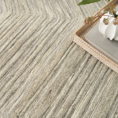 Neutral beige striped textured rug with raised linear ridges; woven basket and white ceramic vase decor on corner.