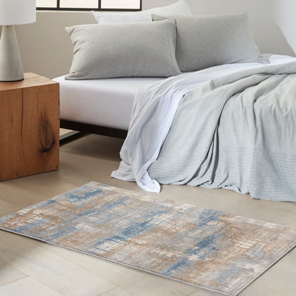 Bed with light gray linens, white sheets, two gray pillows; wooden nightstand, blue-beige patterned rug on light wood floor.