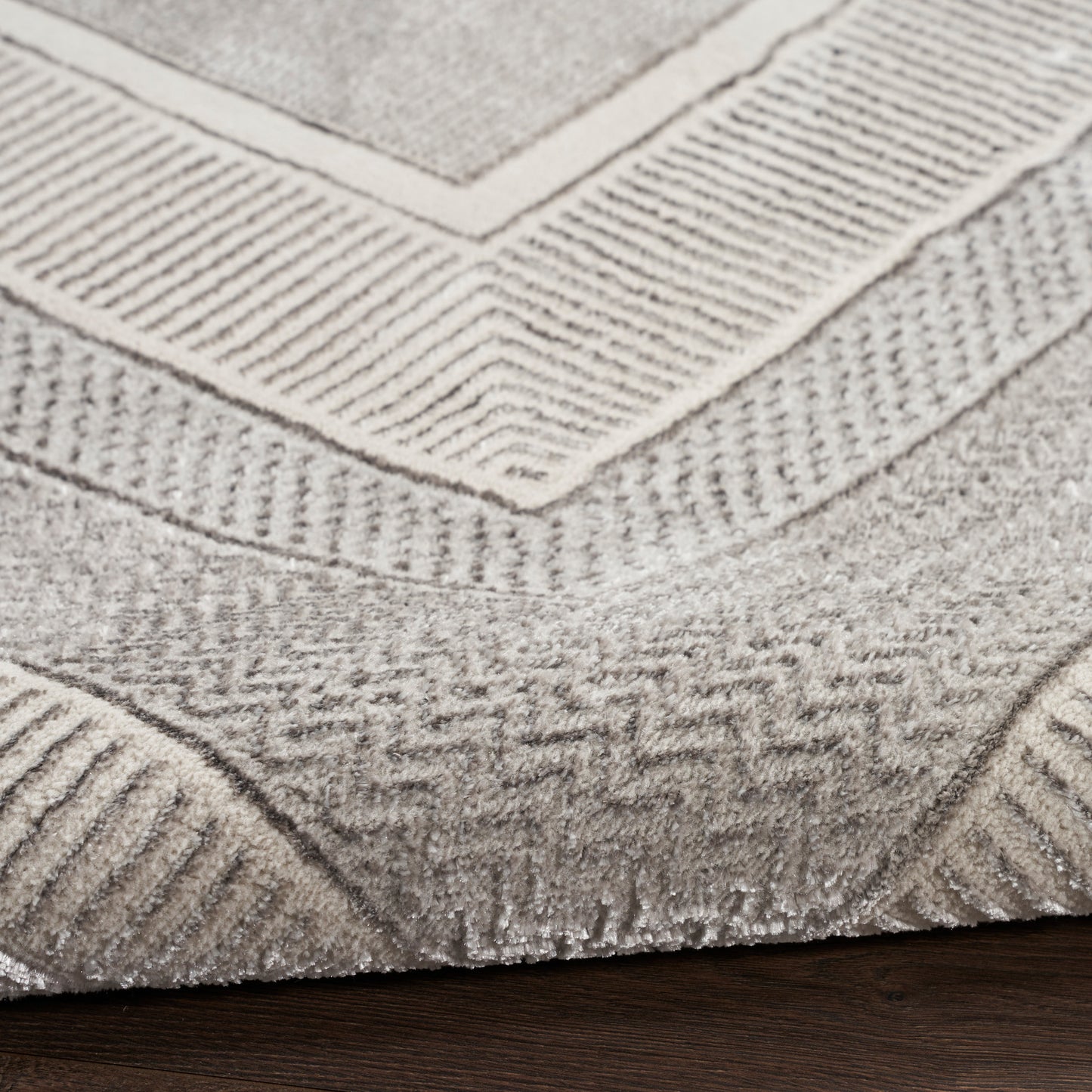 Neutral gray-beige geometric rug with chevron and ribbed border patterns; woven, low-pile.
