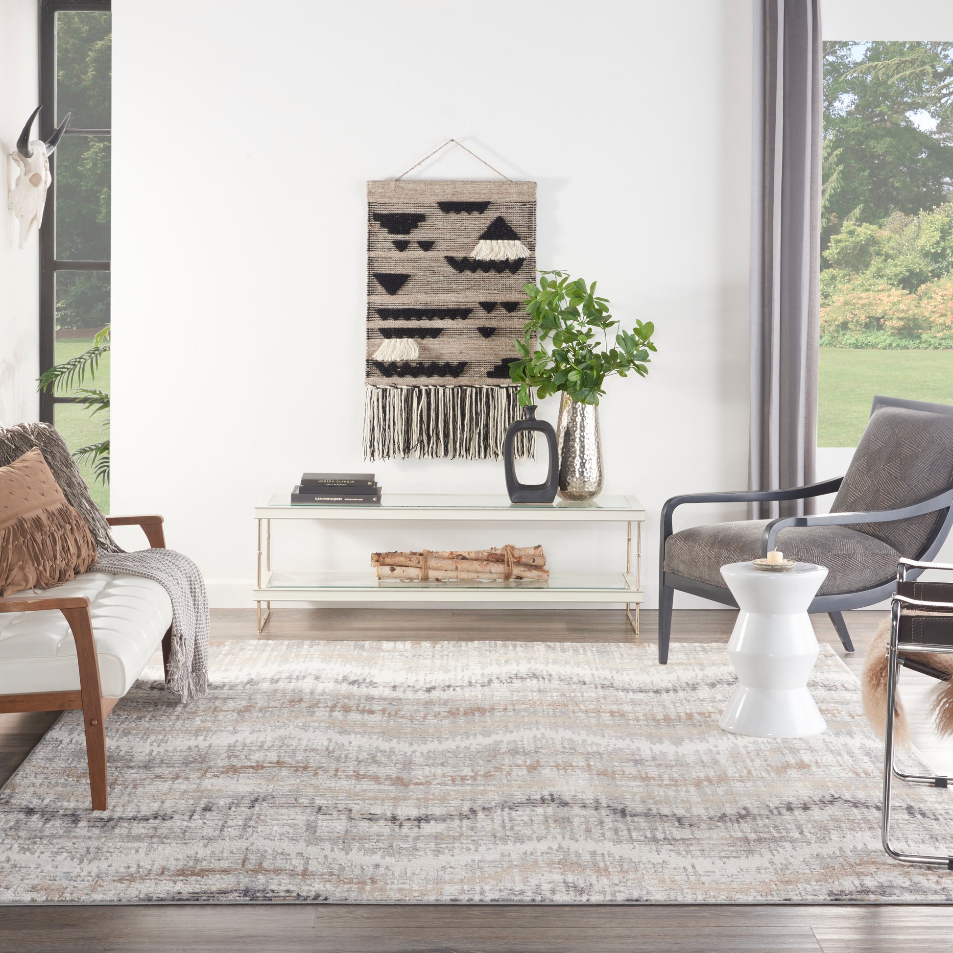 8' x 10' geometric beige-black rug in a modern living room with a glass console table, gray armchairs, and a green plant.