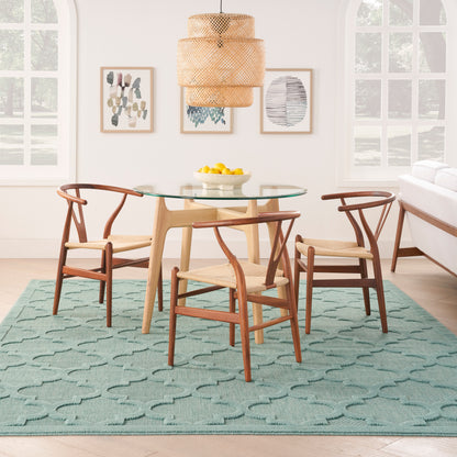 Teal geometric modern rug in a dining-room scene, with a woven pendant lamp, wall art and a bowl of lemons.
