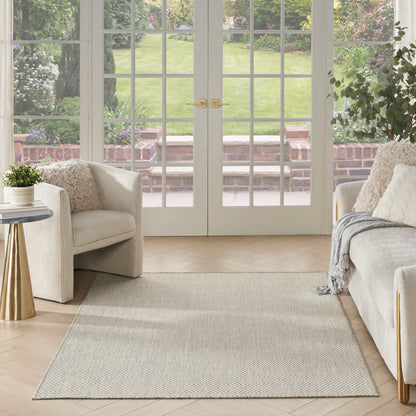 Bright living room with cream sofas, beige textured rug, glass French doors, gold accents, leafy plants, neutral cozy decor.