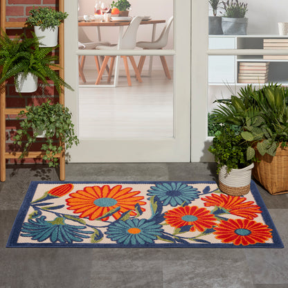 Rectangular outdoor rug with bright orange, teal and blue flowers on a cream background, dark blue border.