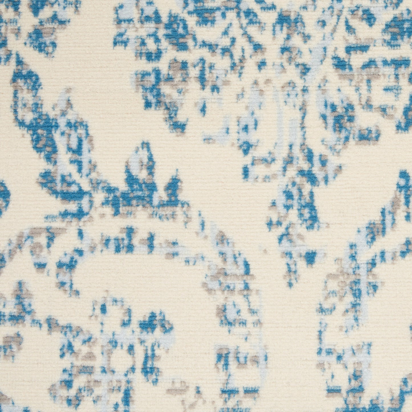 Cream rug with blue damask floral motif and subtle woven texture.