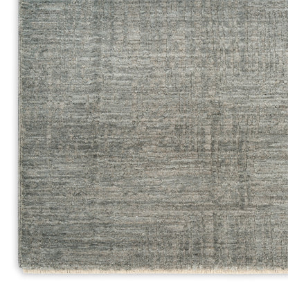 Gray textured rectangular rug with subtle distressed pattern and beige fringe along the bottom edge