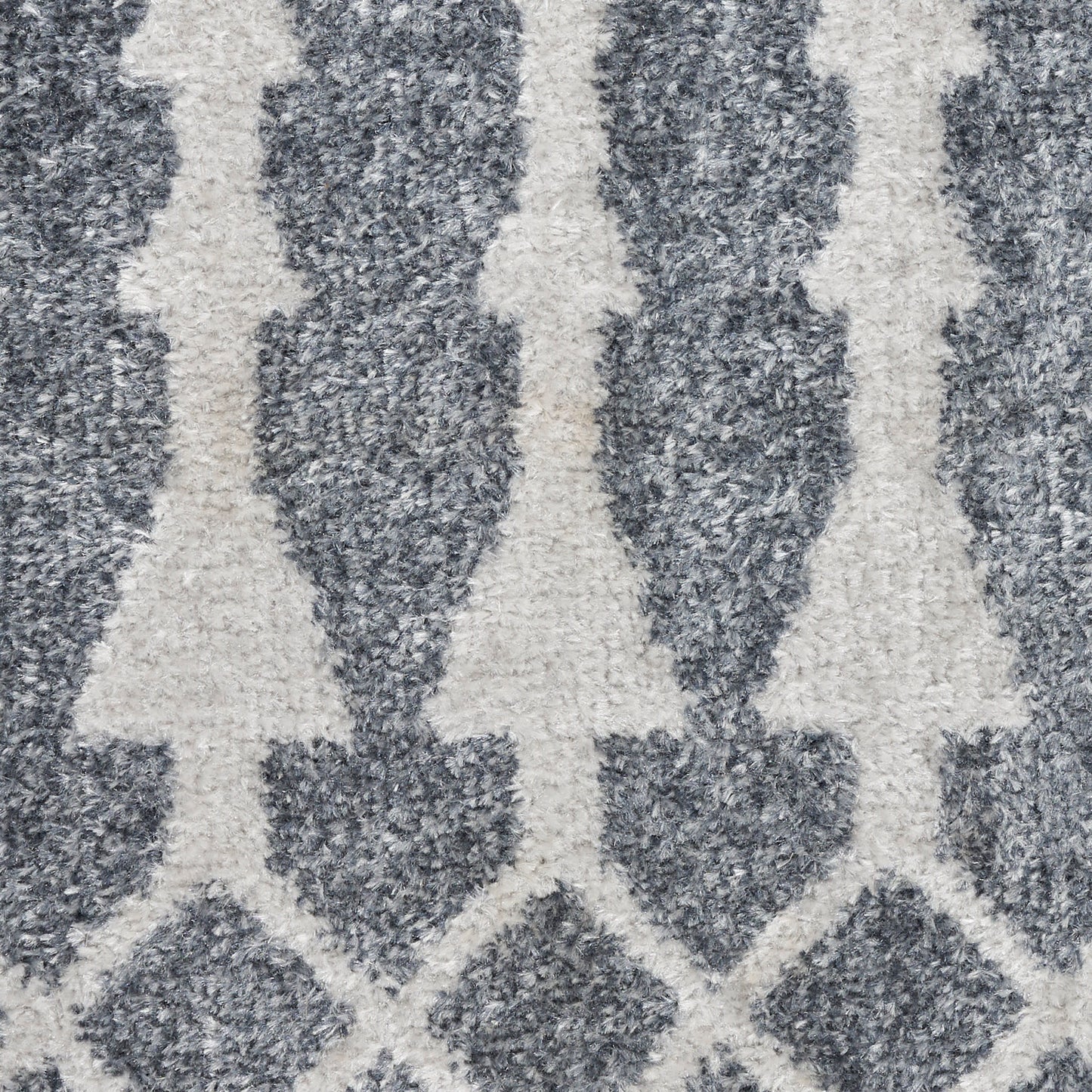 Ivory tree silhouettes in a repeating geometric pattern on a deep blue textured rug.