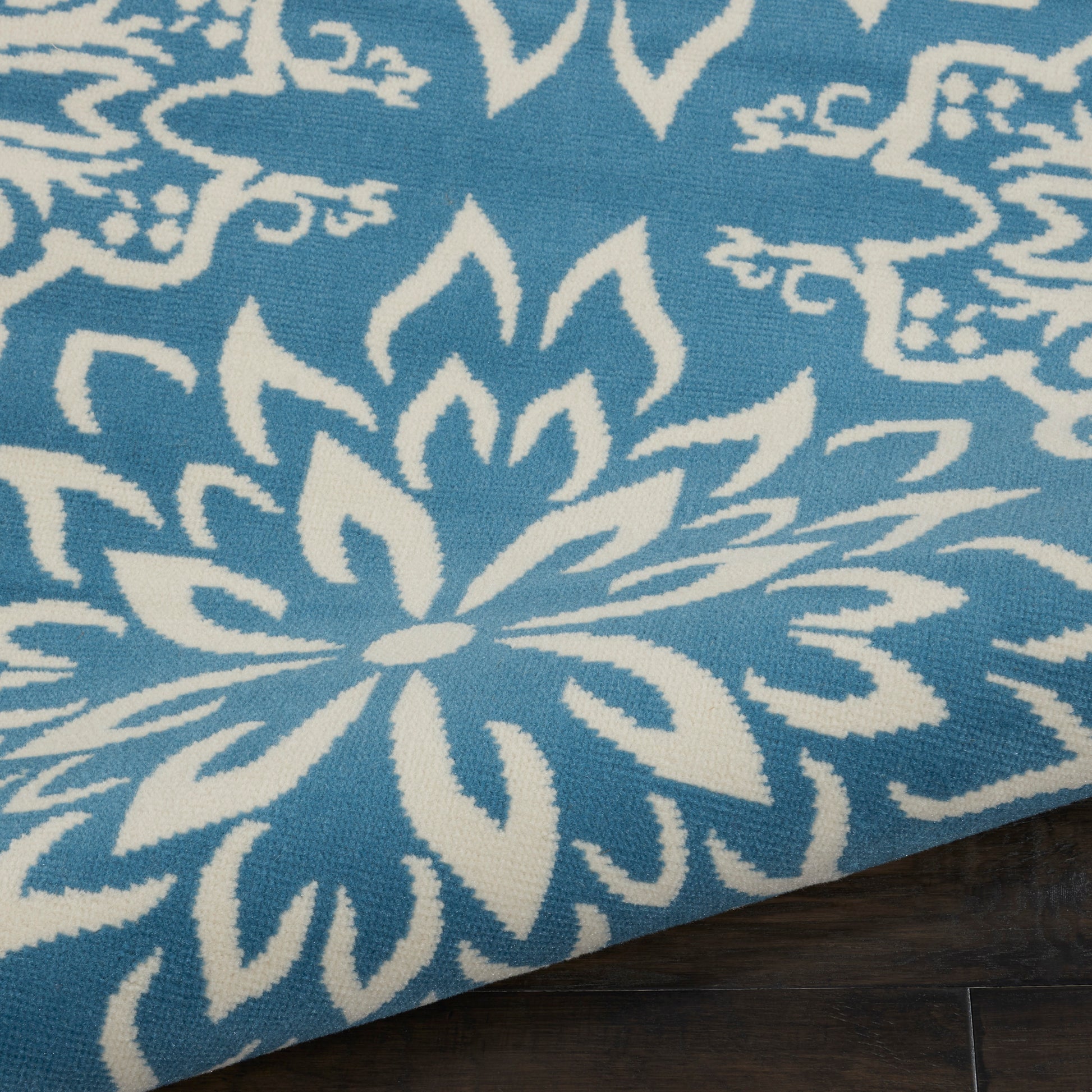 Blue woven rug with large white floral mandala design; decorative floor mat for living spaces.