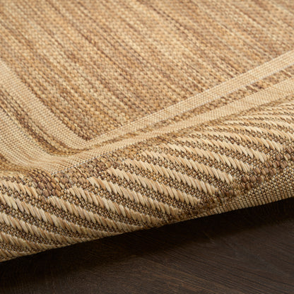 Natural beige woven jute rug with striped pattern and thick braided border, close-up view.