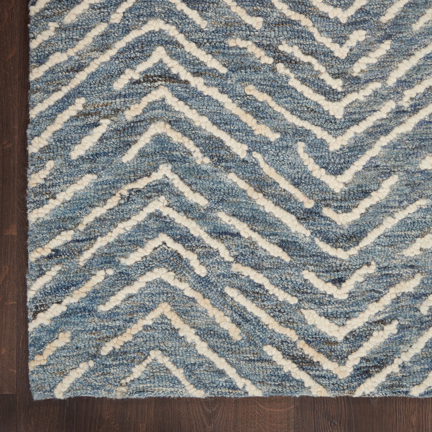 Blue and white chevron shag rug with plush texture on dark wood floor.